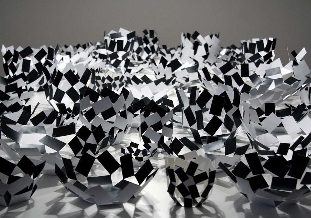 Black-and-white geometric paper sculptures in dynamic, fragmented forms, evoking movement and modern artistry.