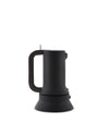 Black matte espresso coffee maker by Alessi with a large loop handle and visible brass pressure valve, shown from the side.