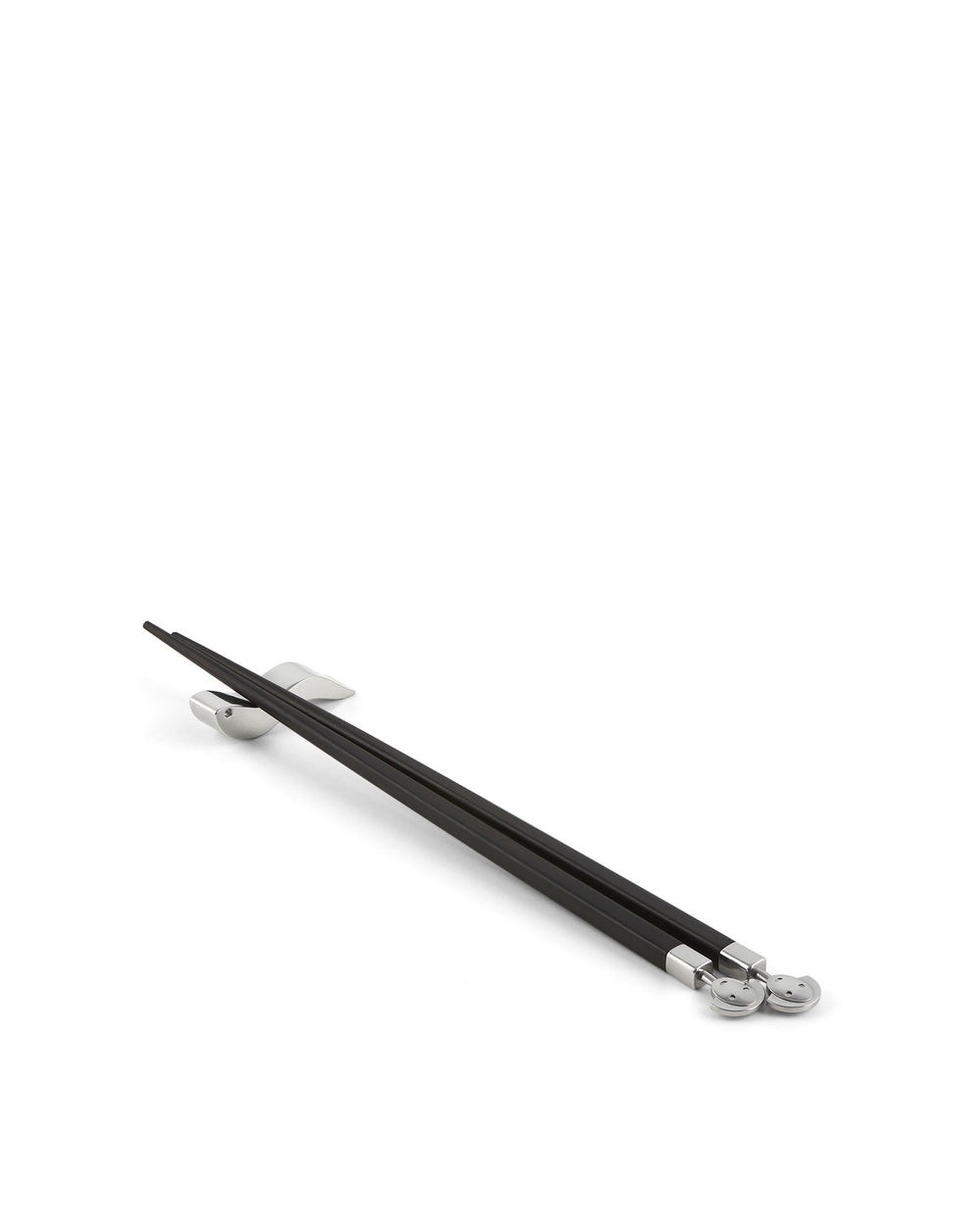 Black chopsticks with silver accents by Alessi, resting on silver chopstick rests, featuring smiling face details.