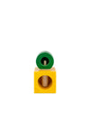 A wooden nutcracker by Alessi, with a green cylindrical top over a yellow cubic base featuring a screw.