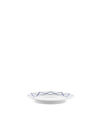 White porcelain saucer by Alessi with a blue geometric pattern, viewed from a low angle.