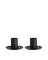 Two matte black cylindrical cups by Alessi with wide flat bases and small grey tabs, placed side-by-side.