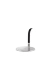 Stainless steel paper towel holder by Alessi with a round base and a matte black, curved upright arm.