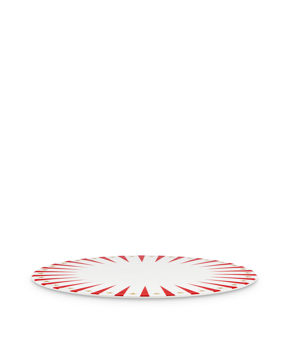 White Christmas decorative plate by Alessi with red sunburst rays and gold stars, angled view.