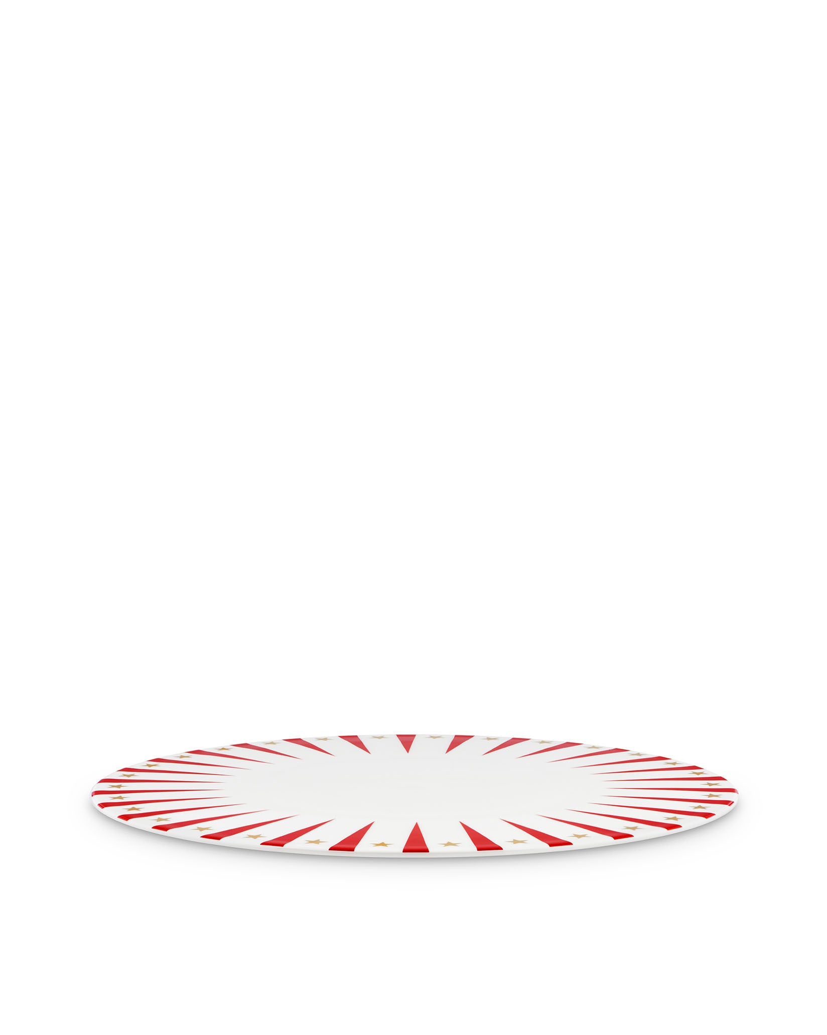White Christmas decorative plate by Alessi with red sunburst rays and gold stars, angled view.