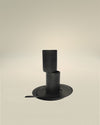 Matte black ceramic cups by Alessi, stacked vertically on a matching saucer with a stirring stick.