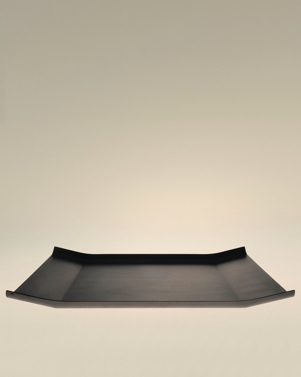 Black rectangular tray by Alessi with flared sides and a minimalist design.