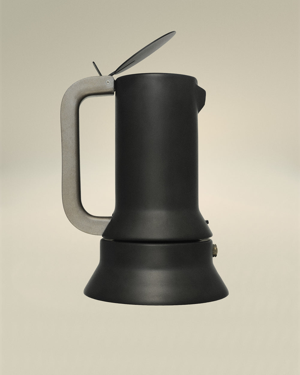 Matte black espresso coffee maker by Alessi with a metallic gray handle and a hinged lid.