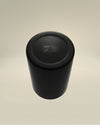 Black matte metal cup by Alessi, viewed from above, showing engraved 'C.P. Company' and 'Design Jean Nouvel' details on its base.
