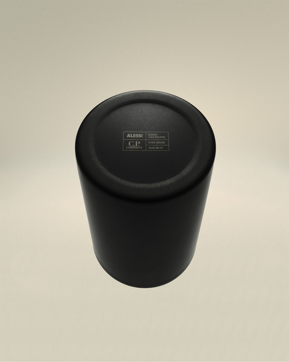 Black matte metal cup by Alessi, viewed from above, showing engraved 'C.P. Company' and 'Design Jean Nouvel' details on its base.