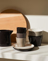 Tonale ceramic cups by Alessi, a stack of dark brown, grey, and beige, with matching pitcher and bowls.