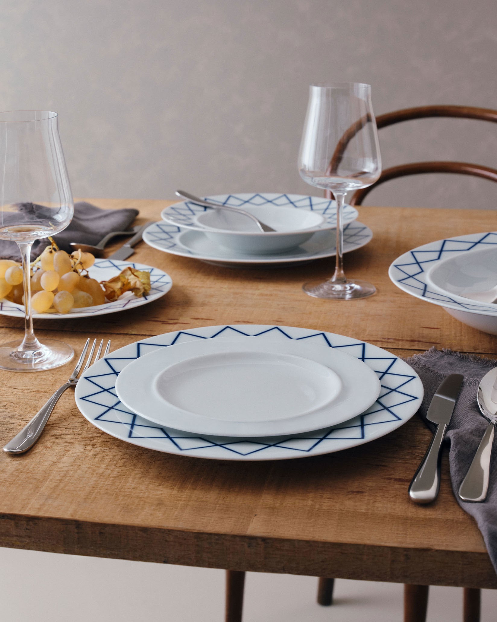 White side plate by Alessi with a blue geometric pattern, styled on a rustic wooden table.