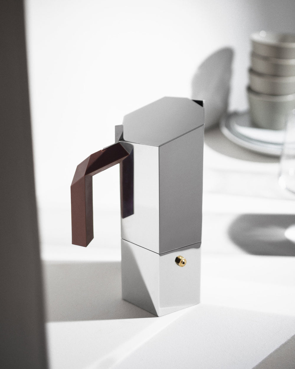 Geometric silver espresso coffee maker by Alessi with brown faceted handle and brass safety valve.