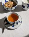 White Yunoki ware table set by Alessi with bold blue abstract designs, showing a bowl, mug, and teacup.