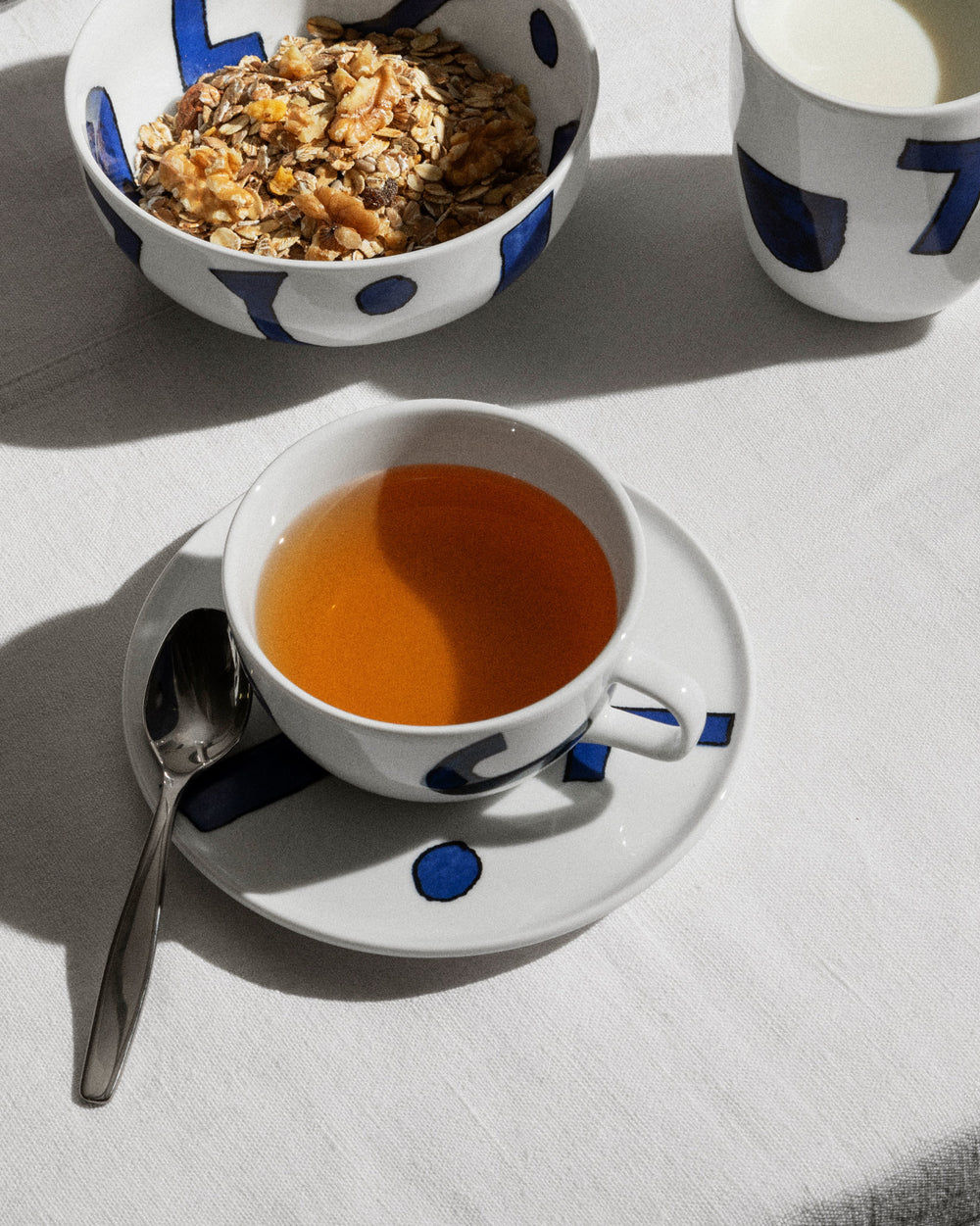 White Yunoki ware table set by Alessi with bold blue abstract designs, showing a bowl, mug, and teacup.
