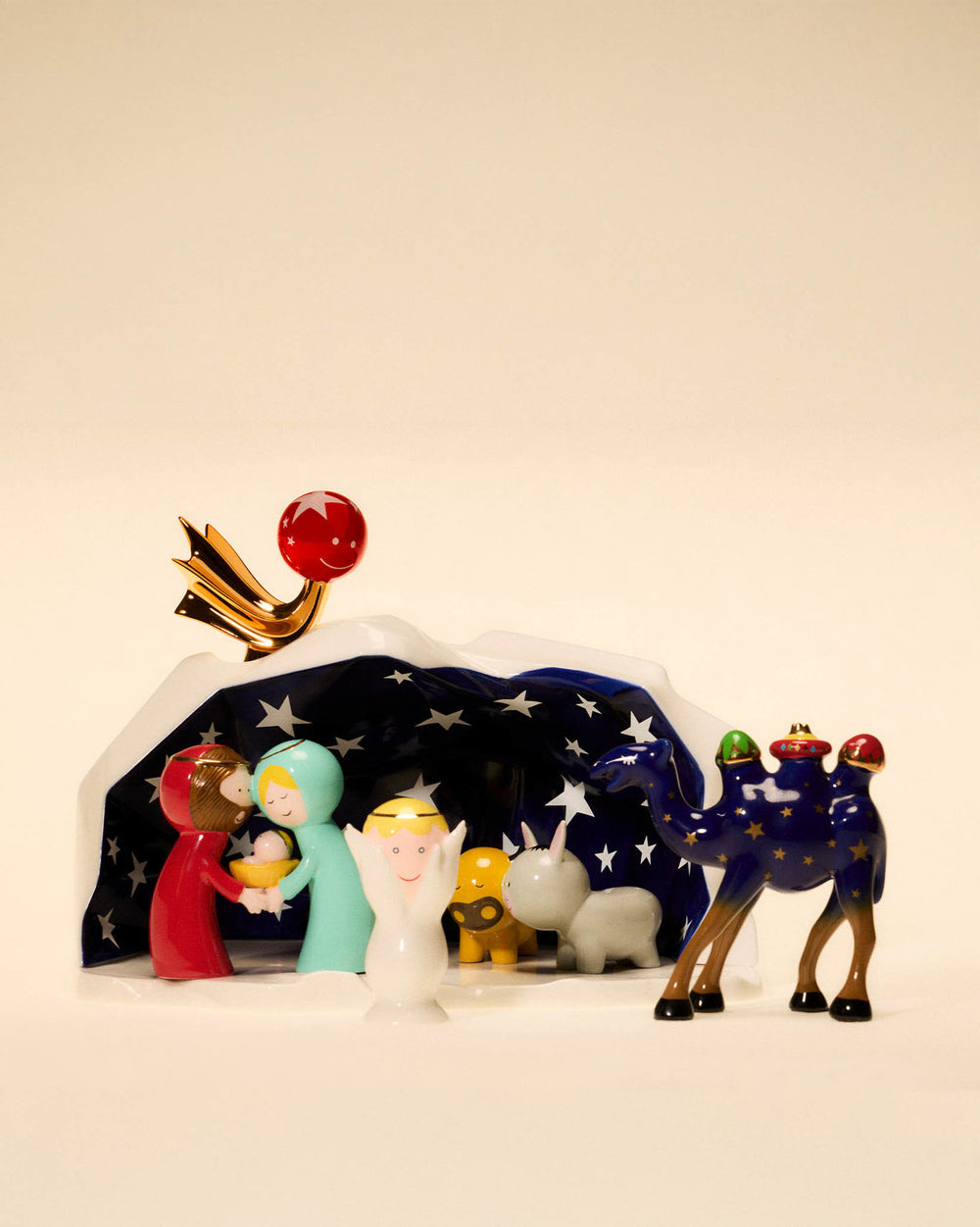 Colorful, glossy nativity set by Alessi, featuring stylized figures, a star-patterned tent, and a red smiling star.