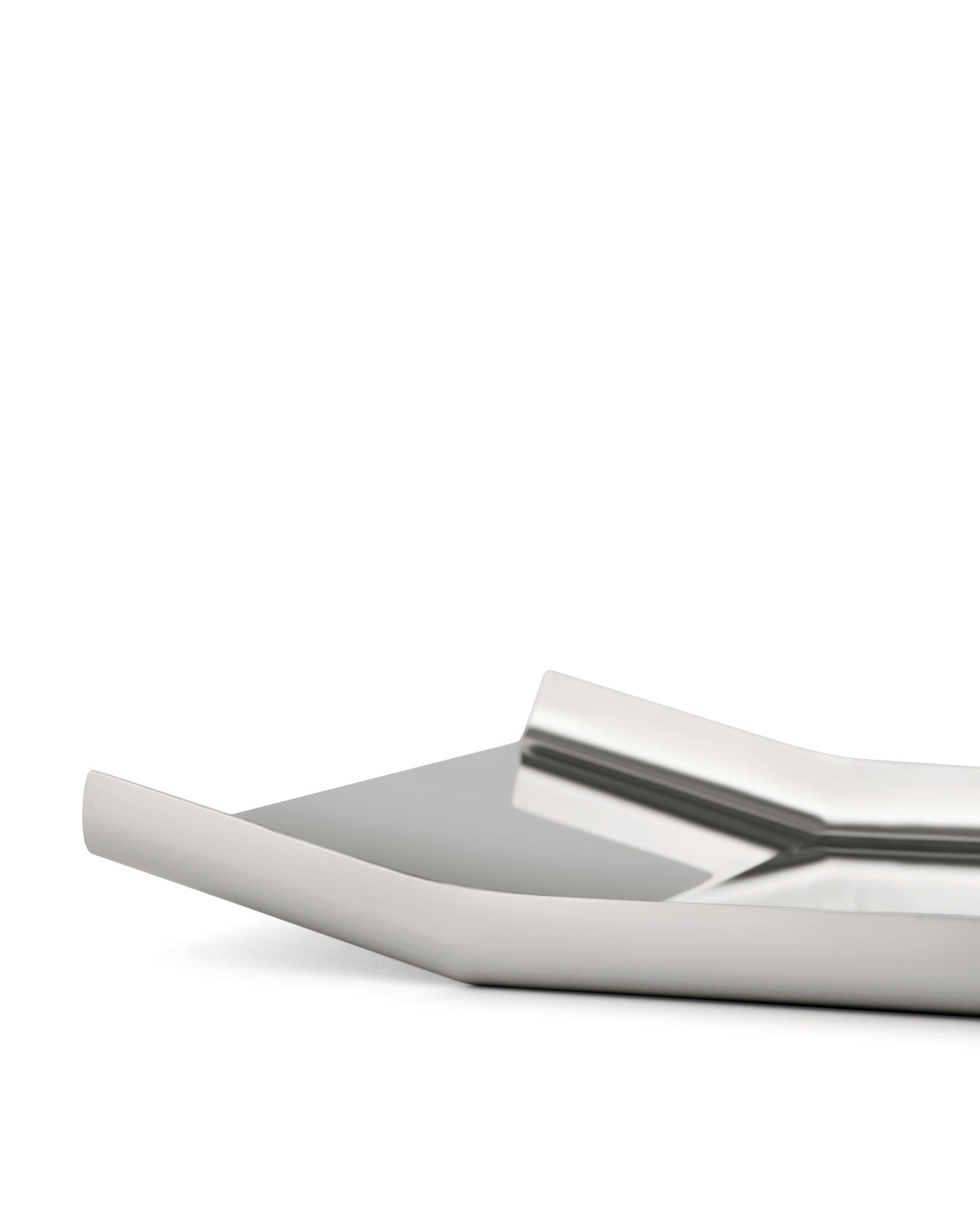 Silver metallic tray by Alessi with a sleek, modern design and reflective surface, viewed from a low angle.