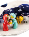 A stylized ceramic Nativity set by Alessi, featuring Mary, Joseph, Baby Jesus, an ox, and a donkey against a star-patterned blue backdrop.