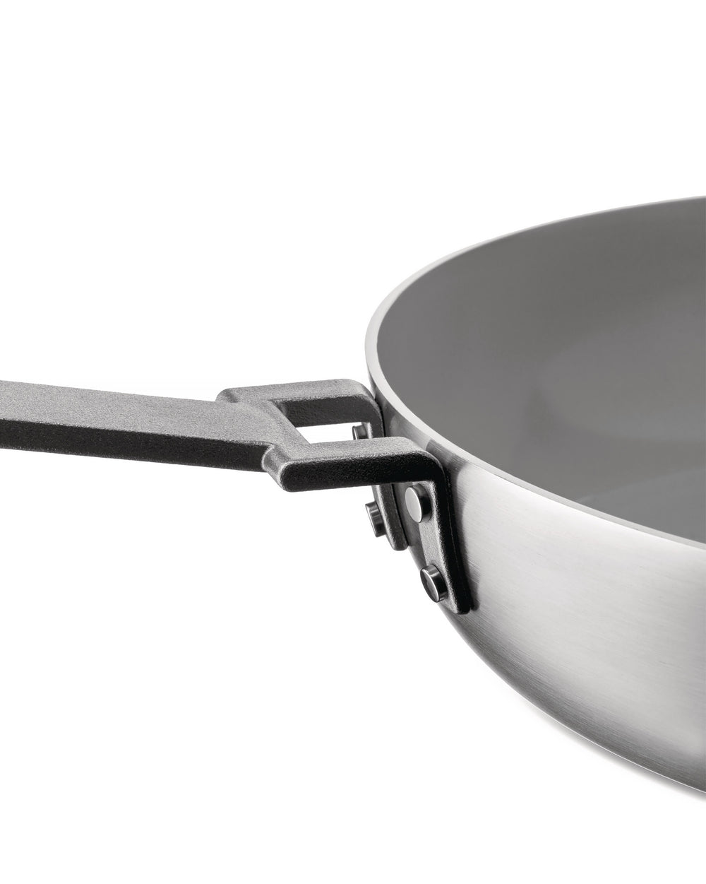 Stainless steel pan with a gray interior by Alessi, featuring a textured black handle attached with rivets, from a side view.