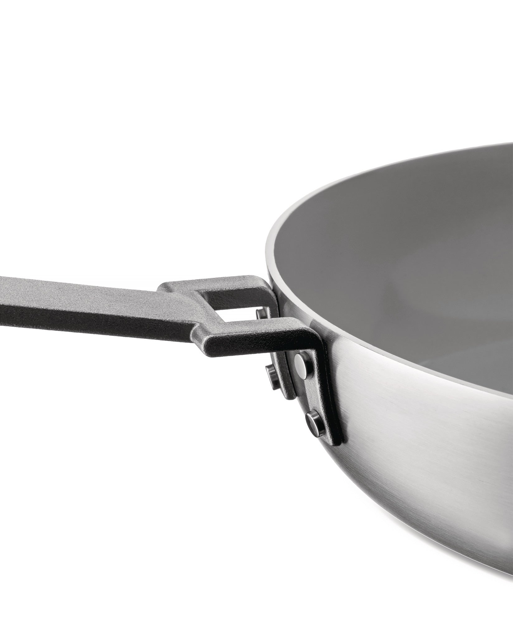Stainless steel pan with a gray interior by Alessi, featuring a textured black handle attached with rivets, from a side view.