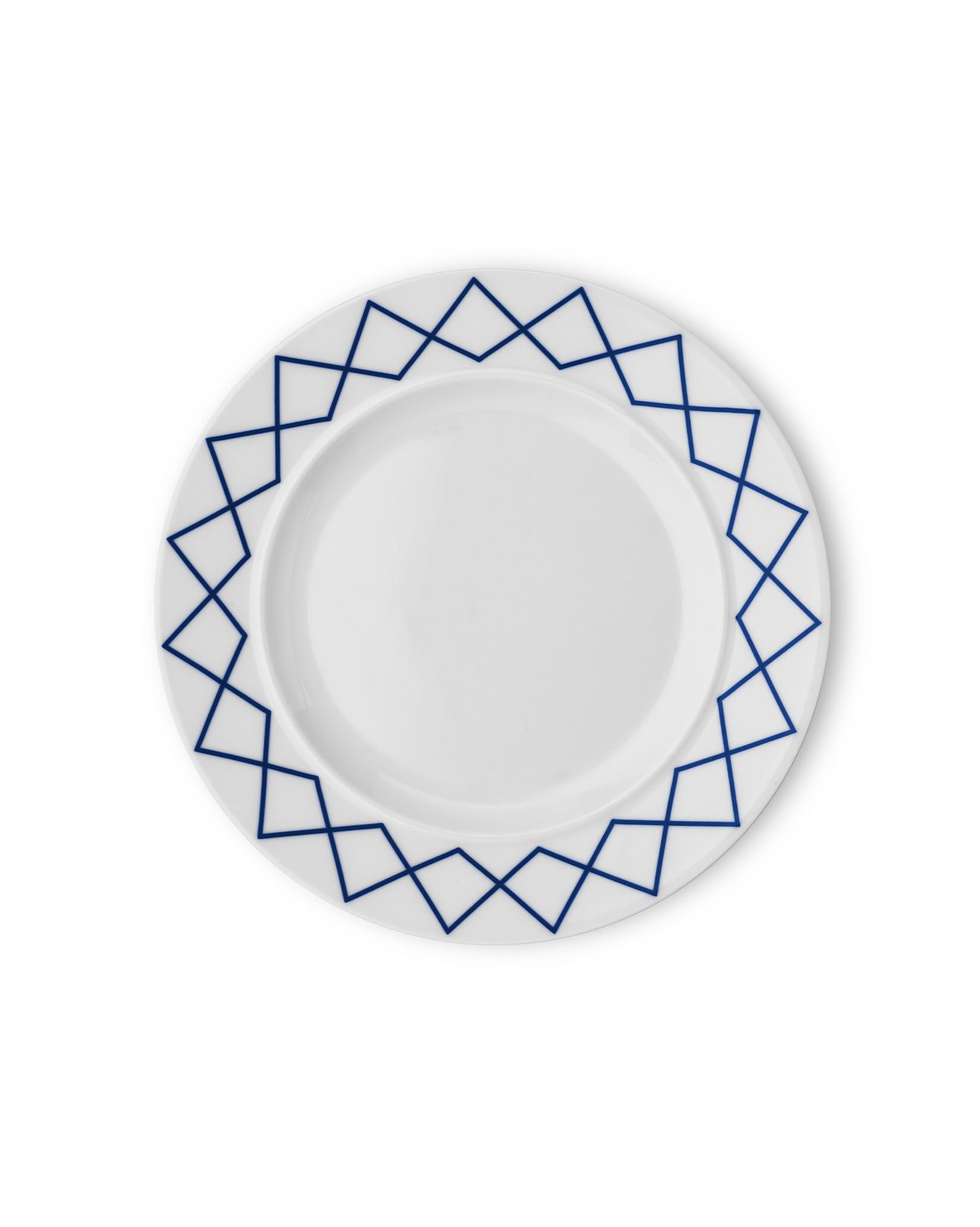 White ceramic dining plate by Alessi with a blue geometric zigzag pattern on the rim, from a top-down view.