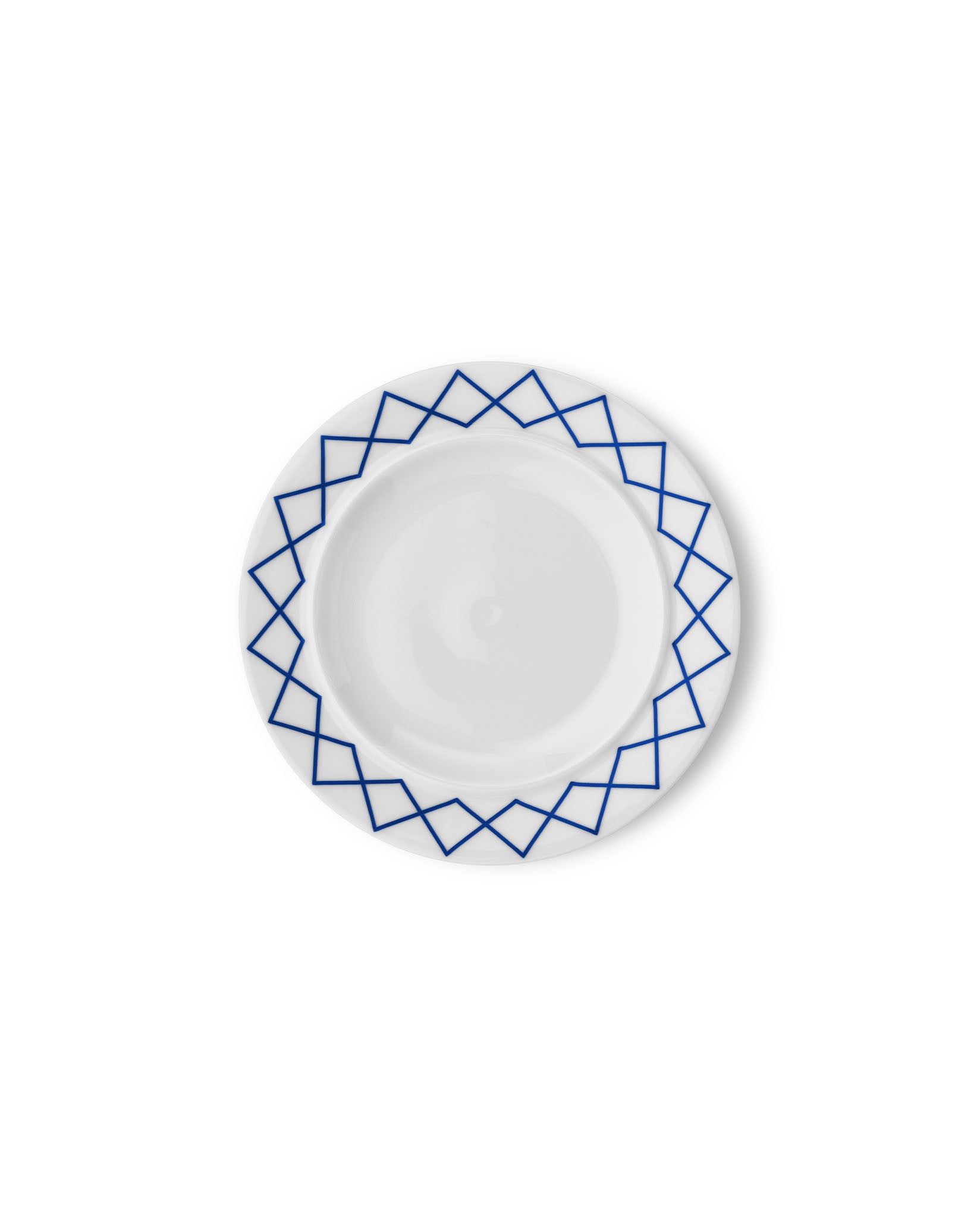 White side plate by Alessi with a blue geometric pattern along the rim, viewed from above.