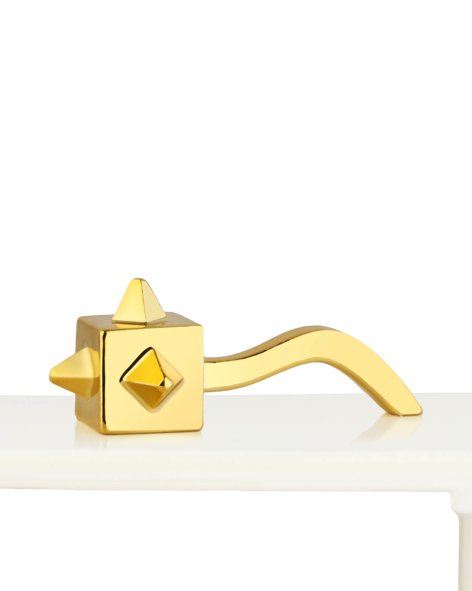 Golden Miracolata ornamental figurine by Alessi, with a spiked cube head, diamond accent, and curved handle, on a white surface.
