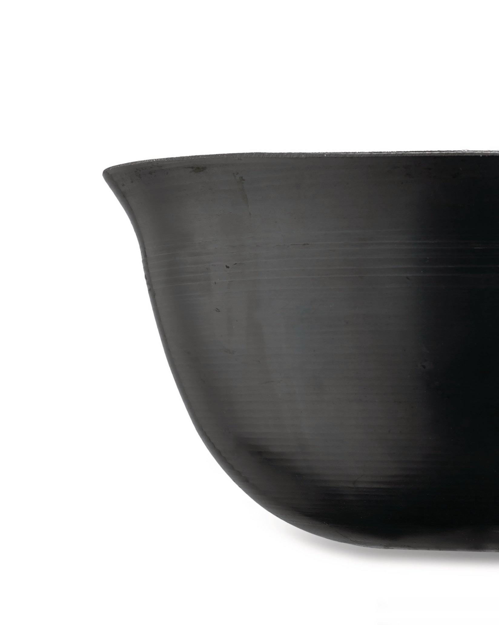 A dark grey bowl with subtle horizontal ridges by Alessi, shown in a cropped side view.