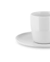 A white ceramic cup and saucer by Alessi, with a glossy finish, shown in a cropped side view.