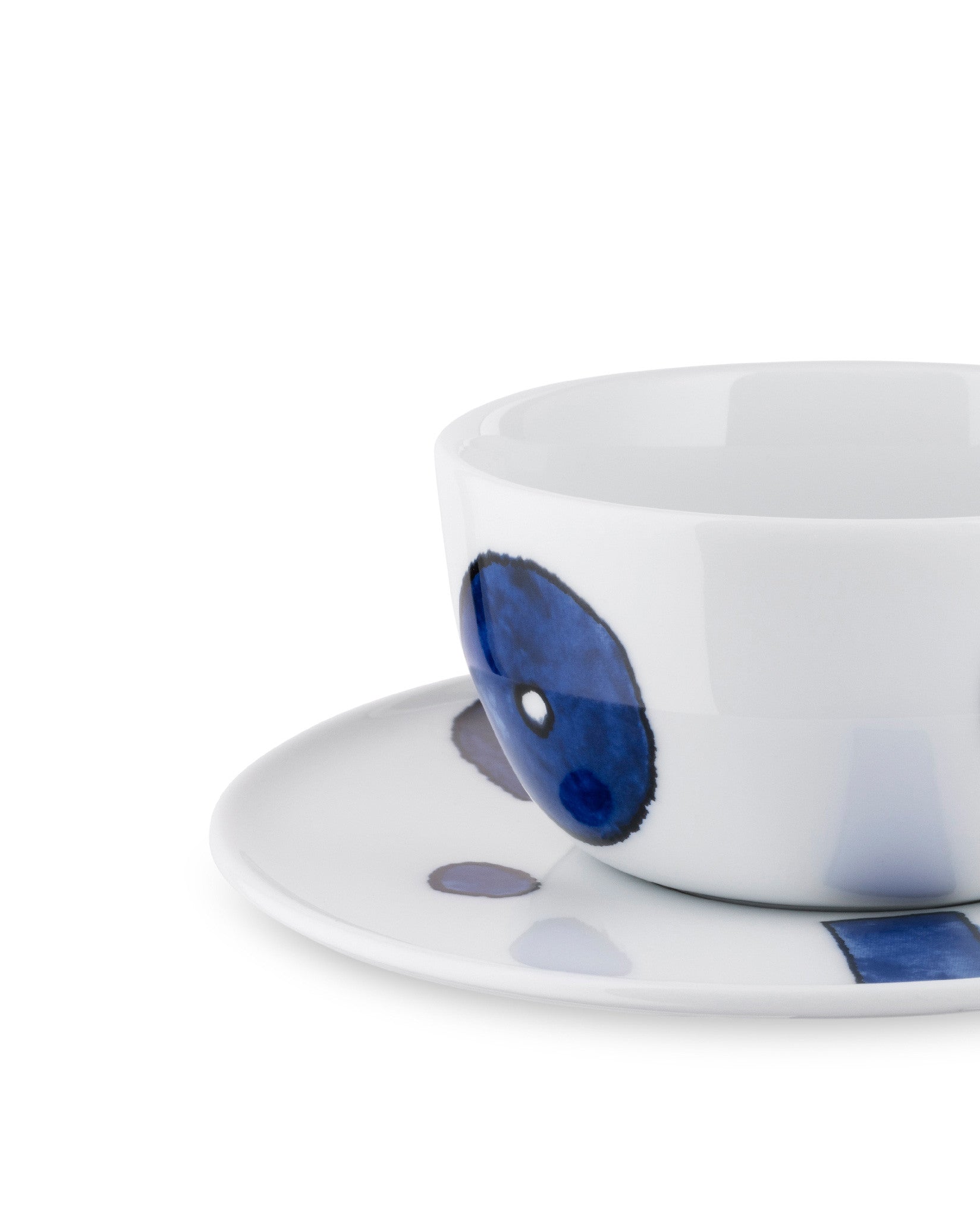 White ceramic cup and saucer by Alessi, decorated with abstract blue and grey circles, cropped close-up.