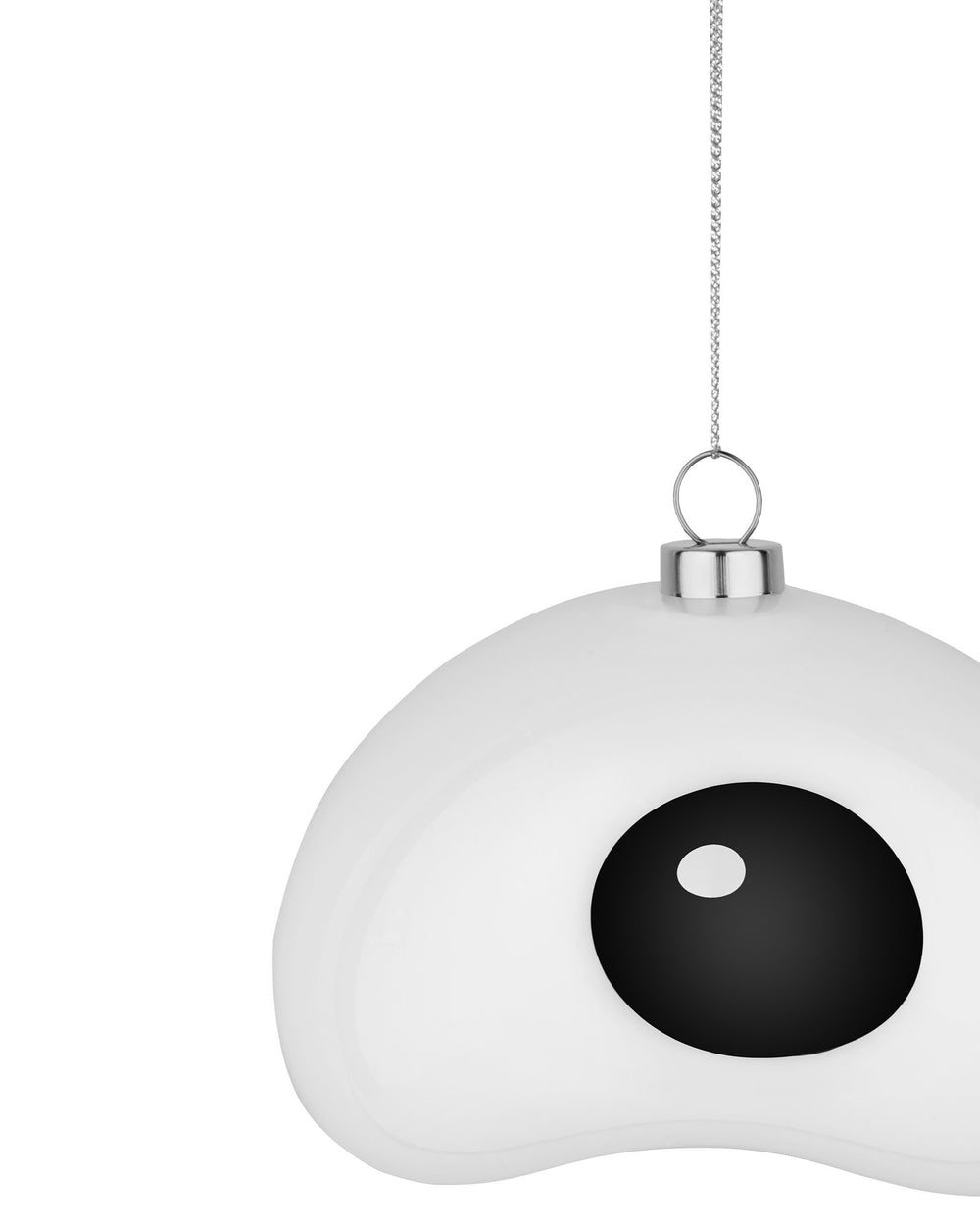 White fried egg Christmas tree ornament by Alessi, with black pupil and white reflection, hanging from silver chain.