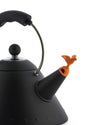 Black matte kettle by Alessi with a whimsical orange bird whistle, steel handle, and subtle raised dots.