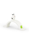 White animal ornamental figurine by Alessi, with black spots and horns, standing on a curved white bridge with a small green plant.