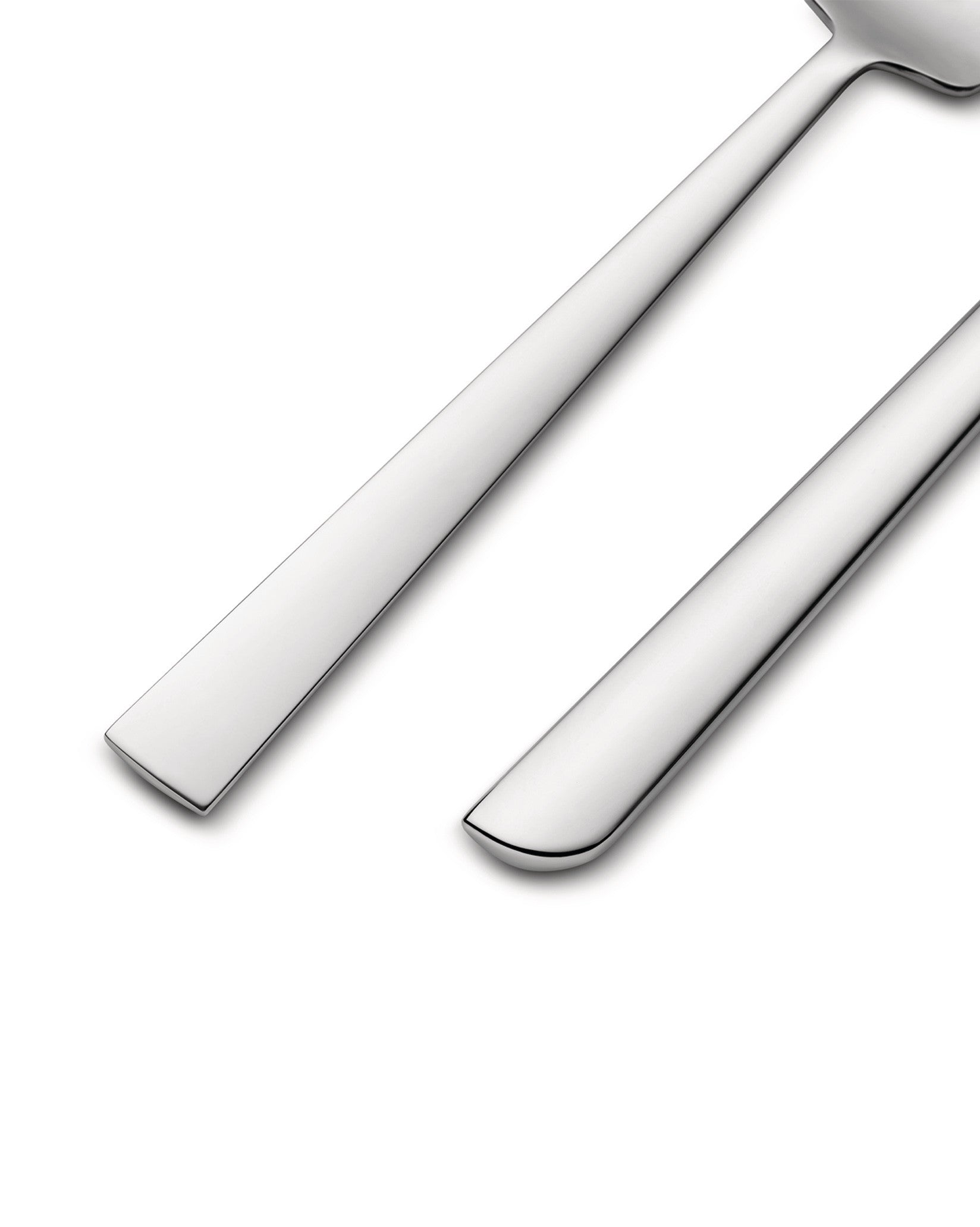 Polished silver flatware by Alessi, with sleek handles angled on a clean white background.