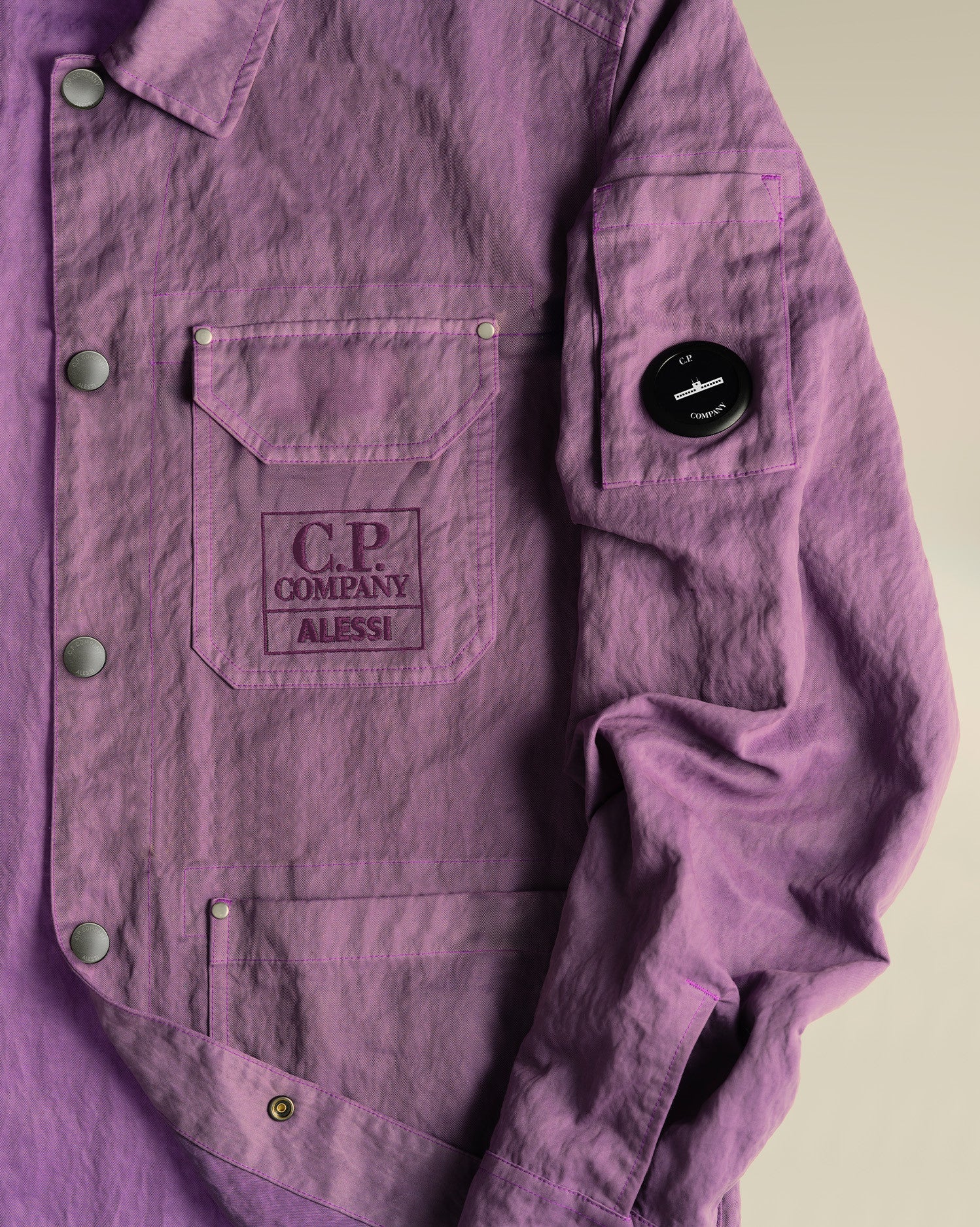 Purple crinkled jacket by Alessi, with C.P. Company chest embroidery and arm lens.
