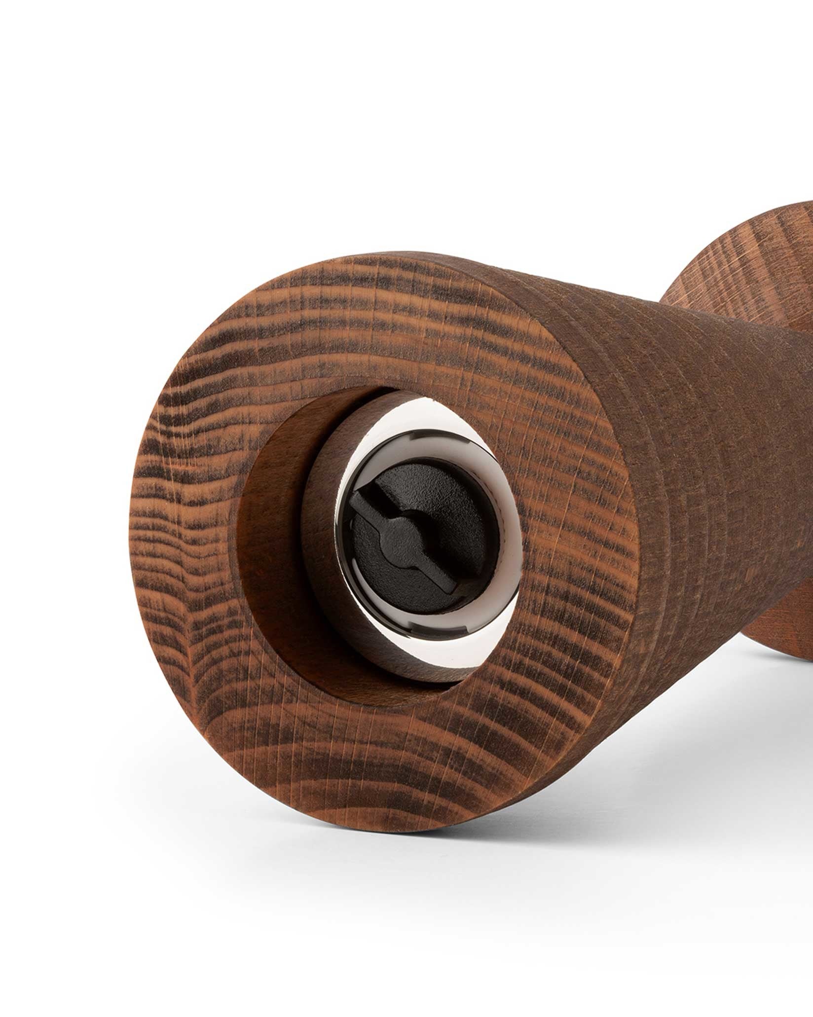 Dark brown wooden grinder by Alessi with a prominent wood grain and a visible black grinding mechanism.