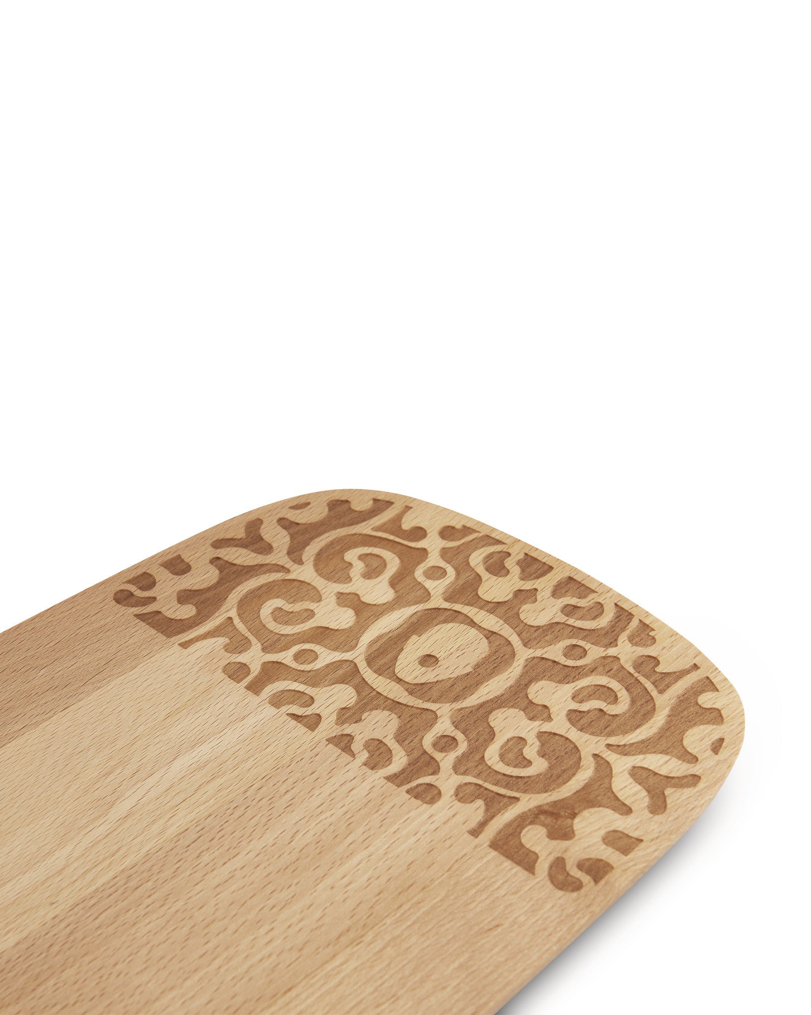 Wooden serving plate by Alessi with a laser-engraved intricate swirling pattern on one rounded end.