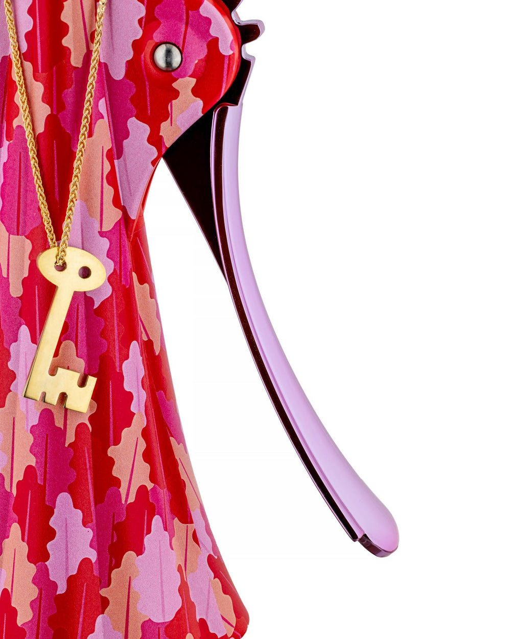 Pink and red patterned Anna G. corkscrew by Alessi, with a shiny purple arm and a gold key necklace.