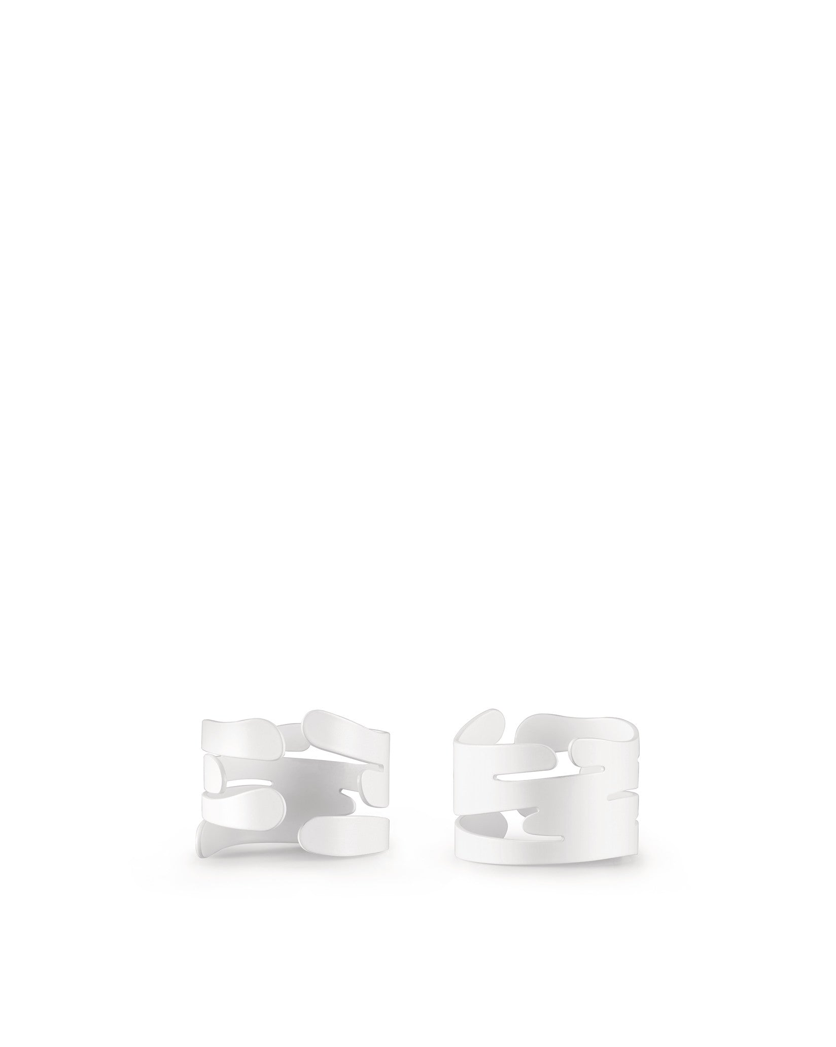 Two white abstract napkin holders by Alessi, with flowing, tree bark-like cut-out designs, shown front view.