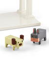Two stylized ceramic nativity animal figures by Alessi, a light yellow dog and a grey donkey, standing on a white surface.
