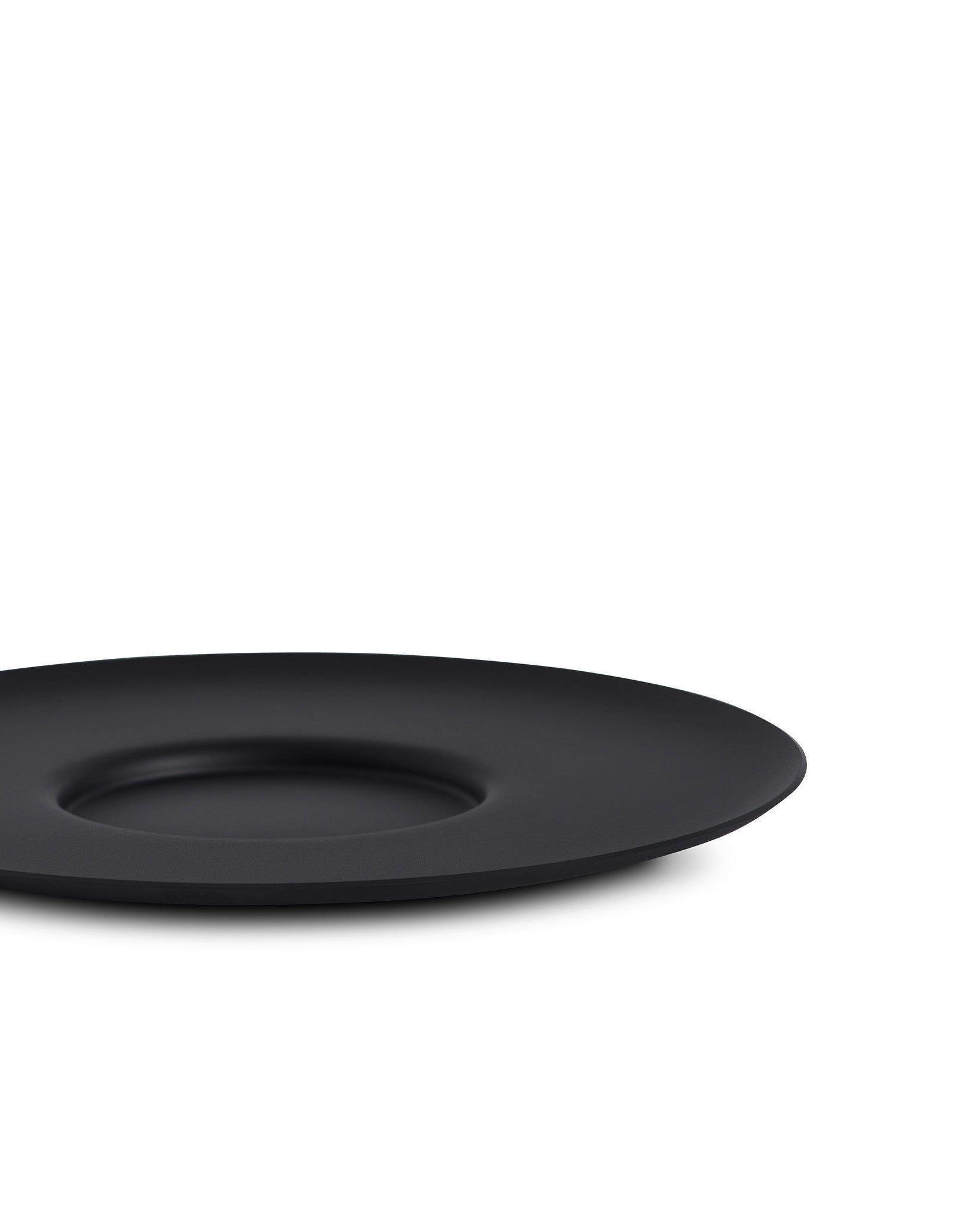 Black matte cup by Alessi, with a wide, shallow profile and subtle central indentation, shown low angle.