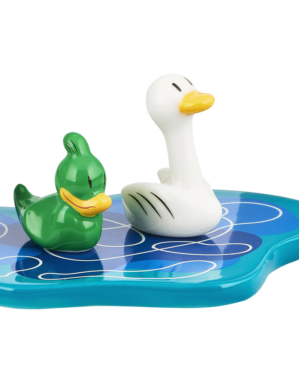 Two ornamental figurines: a green duck and a white swan by Alessi, resting on a blue base with white wave patterns.