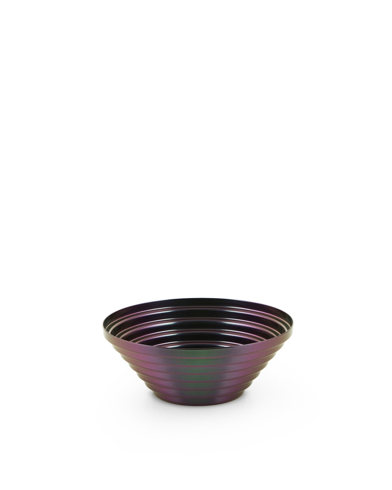 Iridescent dark purple and green metal bowl by Alessi with a ribbed, layered design.