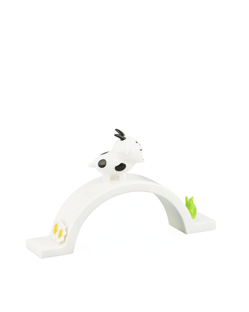 White ornamental figurine by Alessi, featuring a spotted goat on an arch bridge with a flower and a green sprout.