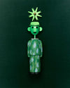 Green corkscrew by Alessi styled as a whimsical figure with a leaf-patterned body and a pinwheel hat.