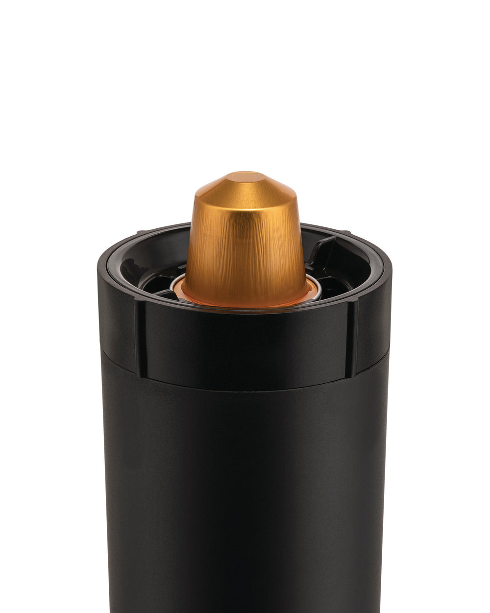 Black cylindrical capsule crusher by Alessi with a golden ribbed coffee capsule inserted at the top.