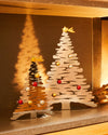 Two gold metallic Christmas tree ornaments by Alessi, with abstract cutout branches, shooting stars, and colorful baubles.