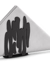 Black metal napkin holder by Alessi with an organic, flowing cut-out design, holding white folded napkins.