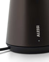 Matte dark brown textured Bedin lamp by Alessi, close-up showing the ALESSI logo and an illuminated light on a black base.