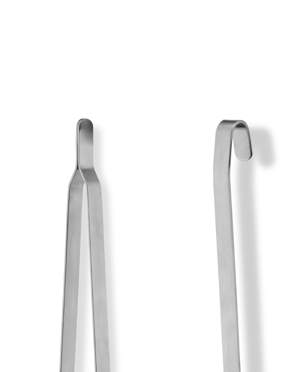 Two brushed stainless steel flatware serving pieces by Alessi, one with a hook top, on a white background.